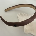 Detalle de diadema de satén marrón acolchada con placa metálica hexagonal de moda fashion - café