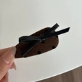 Detail van caramelbruine haarspeld met zwarte stippen op donkere koffiebruine stof - Druppel Strik Stijl / Khaki Waterdruppel Clip met Zwarte Strik