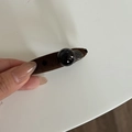 Detail van de karamelbruine stoffen haarclip met een zwarte kraal en gegraveerd metalen label - Ovaal Kralen Stijl / Khaki Ovale Clip met Zwarte Kraal