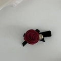 Vista macro del fermaglio per capelli con rosa in raso rosso e rilievo dorato vintage - Fiore Rosso Base Nera