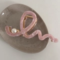 Dettaglio della molletta per capelli rosa ondulata in acetato con perla su vassoio ceramico - Righe Rosa
