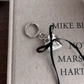 Detail of silver heart keychain with black ribbon bow on a vintage book surface - Silver Heart Black Ribbon