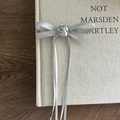 Detail einer silbernen Satin-Schleifen-Haarklammer mit Rose und eleganten langen Bändern - Grau