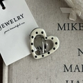 Close-up of heart-shaped hair clip with black polka dots and silver metal duckbill clip - Cream White Black Dot Hollow Heart