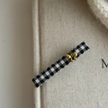 Detail der Haarklammer mit Karomuster, goldener Schleife und eleganten Wellenkanten - Schwarz Weiß Gingham Gold Schleife und Band Schleife Stil