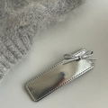 Close-up of a silver leather bow hair clip featuring a metallic texture and stitched edges - Solid Rectangle Silver Bow
