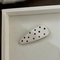 Détail d'une pince à cheveux goutte d'eau blanc crème à pois noirs sur un plateau - Pince Triangulaire Blanc Crème à Pois Noirs