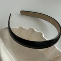 Détail d'un serre-tête minimaliste en similicuir noir sur un plateau en céramique - Noir