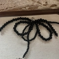 Détail d'un bijou de chaussure en perles noires avec fermoir mousqueton argenté - Pendentif Nœud en Perles Noires