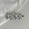 Barrette à cheveux double nœud en métal argenté poli sur fond blanc minimaliste - Style Double Nœud Argent
