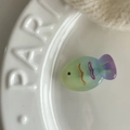 Close-up of translucent gradient fish hair clip with wavy patterns on a ceramic dish - 1# Green Blue Gradient Fish Clip