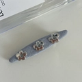 Detail of blue knit hair clip featuring three silver metal flowers with heart centers - Denim Blue