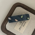 Dettaglio macro del fermaglio in denim con strass colorati su base beige chiaro - Stile Rettangolare con Strass Colorati
