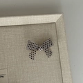 Détail d'une pince à cheveux nœud crème à pois noirs sur un plateau en lin texturé - Pince à Cheveux Nœud Blanc
