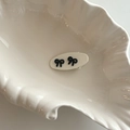 Close-up of a creamy white oval hair clip featuring two elegant black ribbon bows on a dish - White Oval Clip Black Bow