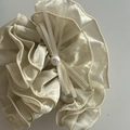 Detalle de coletero de satén crema con bordes plisados y lazo decorado con una perla - Estilo Lazo De Perlas / Champán