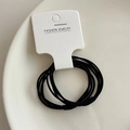 Détail d'un lot d'élastiques à cheveux noirs sur un plateau en céramique blanche - Noir
