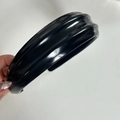 Dettaglio di un cerchietto largo in pelle PU nera con texture plissettata chic - Nero