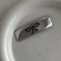 Pince à cheveux en cuir argenté avec un nœud en strass foncés sur une assiette en céramique - Clip Rectangle Argent Nœud Gris