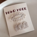 Détail de barrettes à fleurs en dentelle crème sur une carte de présentation fait main - Blanc Cassé Ajouré Ovale