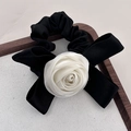 Chouchou élégant avec rose blanche en tissu et nœud en satin noir sur plateau bois - Blanc