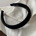 Dettaglio del cerchietto in raso nero testurizzato con etichetta fatta a mano su tessuto beige - Versione Larga / Nero