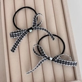 Detail view of two checkered bow hair ties with crystal hearts on a beige velvet tray - Black Bowknot Hair Tie