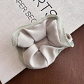 Detailed view of beige satin scrunchie with green zigzag stitching on white background - Green Gauze Edge Off-White Scrunchie