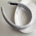 Dettaglio della fascia larga grigio argento con trama pieghettata ed etichetta a mano - Blu