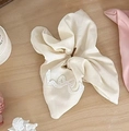 Détail d'un chouchou beige à nœud avec broderie en dentelle et plis de tissu doux - Blanc Cassé