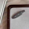 Primer plano de una pinza para el cabello rosa pastel mate sobre lino blanco liso - Gris