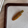 Detalle de pasador ovalado de resina ámbar con clip de pico de pato metálico verde mostaza - Caramelo