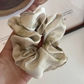 Grande elastico in seta con stampe di foglie verdi tenuto in mano per l'acconciatura - Scrunchie / Scrunchie Marmo Champagne