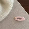 Détail d'une pince à cheveux mate rose avec un nœud doré sur fond de tissu - Pince Bec de Canard Ovale Rose avec Nœud Doré