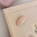 Detail van roze en gele ovale hars haarclip op een zacht getextureerd beige dienblad - Roze Ovale Haarclip