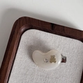 Dettaglio molletta in acetato crema con orsetto dorato e strass su vassoio di lino - Stile Orso Anacardio Bianco Trasparente