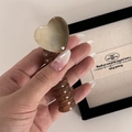 Close-up of amber resin heart-shaped hair claw clip with spiral handle design - Milk Tea White