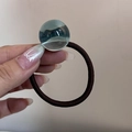 Dettaglio di un elastico per capelli marrone con una perla decorativa in resina blu - Corda per Capelli con Perlina Blu Lago
