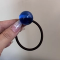 Dettaglio ravvicinato di una sfera di resina blu su un elastico per capelli marrone - Corda per Capelli con Perlina Blu