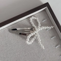 Gros plan d'une pince à cheveux argentée avec perles blanches sur tissu gris - Nœud Perles Blanches Pince BB (2#) / Clips BB / Blanc