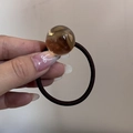 Gros plan sur la perle ambrée translucide et l'élastique à cheveux marron souple - Corde à Cheveux Perle Café
