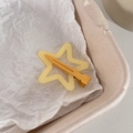 Gros plan d'une pince à cheveux jaune en forme d'étoile sur fond de papier blanc - Jaune Gingembre