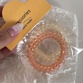 Nahaufnahme von orangefarbenen und gelben Spiral-Haargummis auf Kartonverpackung - Orangegelber Spiralstil