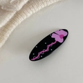 Detail einer ovalen schwarzen Haarspange aus Acryl mit lila Blumenmuster und rosa Linien - Schwarz Mit Großer Schleife