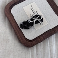 Close-up of black tweed hair clip with a silver metal bow and shiny sequins detail - Black Wave Bow
