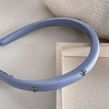 Detail eines hellblauen Satin-Haarreifs mit silbernen Metallschleifen auf Schwamm - Blau