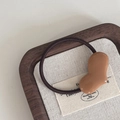 Detail of coffee-colored heart resin charm on elastic brown hair tie over wooden tray - Heart Hair Tie / Coffee
