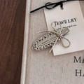 Detail of silver bow hair clip with chain texture and glitter finish on a white card - Gold Ribbon Style