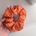 Detalle de un coletero de tela naranja con una etiqueta blanca de la marca FMdrea - Naranja