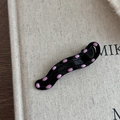 Détail d'une pince à cheveux noire ondulée à pois roses avec une finition brillante - Style à pois creux goutte d'eau irrégulier